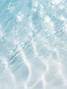 water ripples over the surface of a blue pool with white sand and pebbles on the bottom