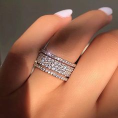 a woman's hand with two wedding bands on her finger and one ring in the middle