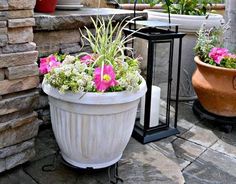 two flower pots sitting next to each other on top of a stone floor near a brick wall