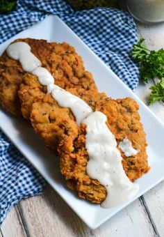 two fried chicken patties with ranch dressing on a white plate