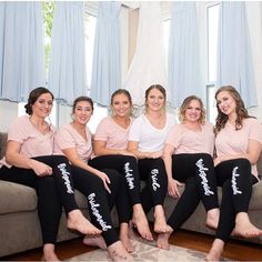 a group of women sitting on top of a couch wearing matching pink and black pajamas