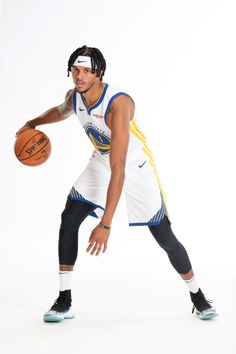 a man holding a basketball while standing in front of a white background with his hand on the ball