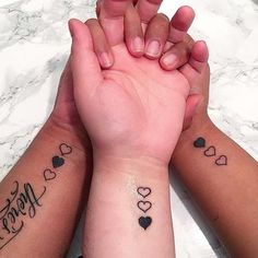 two people holding hands with tattoos on their arms and the words love are written in small hearts