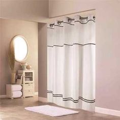 a bathroom with a white rug and shower curtain in front of a mirror on the wall