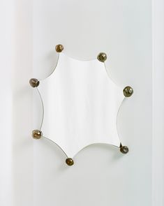 a mirror mounted to the side of a wall next to a white wall with balls on it