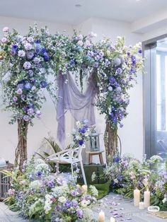 an arrangement of flowers and greenery on display in a room with large glass windows