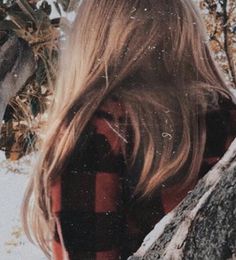 a woman standing in the snow with her back to the camera, looking at trees