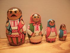 a group of nesting dolls sitting next to each other on a wooden table in front of a wall