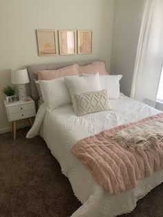 a bed with pink and white comforter in a bedroom next to a window on carpeted floor