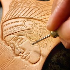 a person using a pen to draw an intricate design on a piece of brown leather