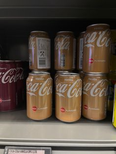 several cans of coca - cola are on display in a grocery store's refrigerator