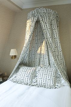 the canopy bed is made up with white sheets and blue polka doted drapes