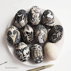 a white plate topped with black and white painted eggs next to a marker pen on top of a table