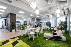 people are sitting in an office with artificial grass on the floor and green plants on the walls