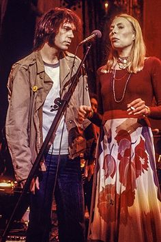 a man and woman standing next to each other in front of a microphone on stage