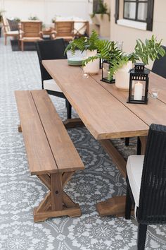 a wooden table with two benches next to potted plants and candles on top of it