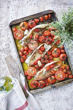 a pan filled with fish and tomatoes on top of a table