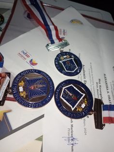 three medals are laying on top of a piece of paper with other items around it