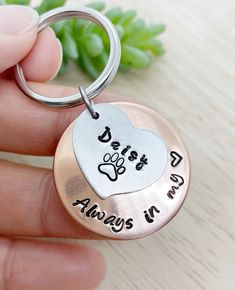 a person holding a dog's paw and heart shaped keychain