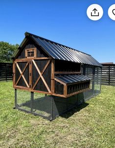 a chicken coop in the middle of a grassy field with a blue sky behind it