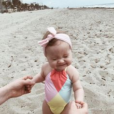 a baby wearing a colorful swimsuit on the beach