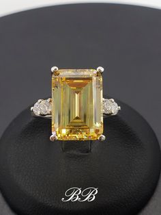 Made to order.  Please allow up to 3 weeks for production. This listing is for a 925 unplated sterling silver ring with a high quality canary yellow emerald cut cubic zirconia diamond and your choose of ring setting. Center Stone Gem Type:  Lab Created Cubic Zirconia Diamond Shape: Emerald Cut Size: 14x10mm Weight: 8.5 carats approximately Color: Canary Yellow Quality: 5A Hardness: 8.5 Mohs Accent Stones Gem Type:  Lab Created Cubic Zirconia Diamond Shape: Round Brilliant Size: (4) 3mm Color: White Quality: 6A Hardness: 8.5 Mohs Ring Setting Options Multi-Stone (As shown in photos) Three Stone Ring (example - www.etsy.com/listing/1280862056) Solitaire Ring (example - www.etsy.com/listing/1264625901) Did you know there are different grades of cubic zirconia? (A - 6A) The higher the grade, t Canary Yellow Diamond Ring Emerald Cut, Yellow Diamond Engagement Ring Emerald, Luxury Yellow Gold Emerald Cut Gemstones, Yellow Emerald Cut Engagement Ring, Yellow Emerald Engagement Ring, White Gold Jewelry With Brilliant Cut Citrine, White Gold Citrine Jewelry With Brilliant Cut, Yellow Diamond Emerald Cut Ring, Yellow Topaz Ring With Center Stone In Sterling Silver