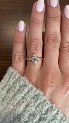 a woman's hand with a pink manicure and a diamond ring on it