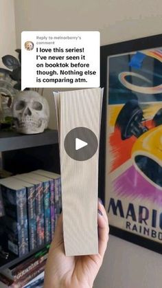 someone is holding up a fake book in front of a shelf with books on it