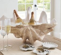 two bottles of champagne sitting on top of a table next to plates and wine glasses