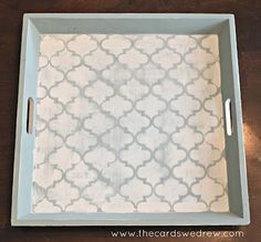 a tray with white and gray designs on the bottom is sitting on a wooden table