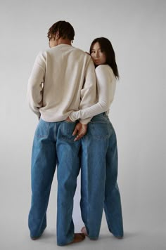 two people standing back to back in jeans and sweaters