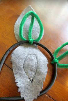 a mickey mouse ears headband made out of felt and green hair ties on top of a wooden table