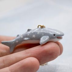 a tiny dolphin ornament is being held in someone's hand with a gold chain