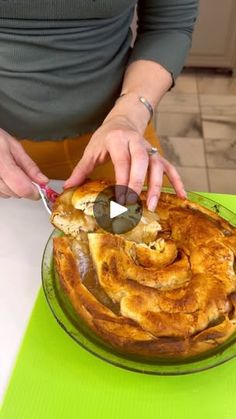 a person cutting into a pie on top of a green table