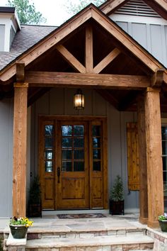 the front entrance to a house with two large wooden doors and steps leading up to it