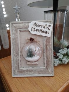 a christmas ornament in a frame on top of a table next to a lamp