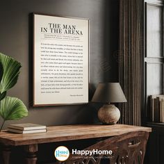 a table with a lamp and some books on it next to a large framed poem