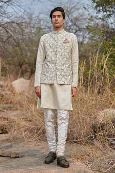 White bundi with zardozi, resham, cutdana embroidery in floral pattern. Paired with textured stripe pattern kurta and churidar. - Aza Fashions Eid Nehru Jacket With Cutdana On Raw Silk, Festive Unstitched Cotton Silk Nehru Jacket, White Fitted Cotton Silk Bandhgala, Designer Nehru Jacket With Gota Work For Eid, Fitted Chanderi Bandhgala For Reception, Festival Nehru Jacket With Intricate Embroidery In Raw Silk, Transitional Chanderi Nehru Jacket For Reception, Eid Nehru Jacket With Gota Work In Chanderi, Wedding Nehru Jacket In Chanderi With Cutdana