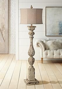 a lamp that is on top of a wooden floor in front of a white couch