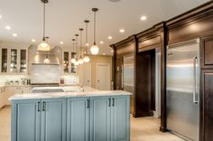 a large kitchen with an island in the middle and lots of lights hanging from the ceiling