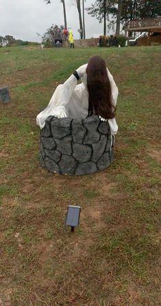 a woman sitting on top of a tire covered bench in the middle of a field