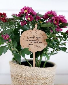 a potted plant with purple flowers and a wooden sign that says thank you for helping us grow