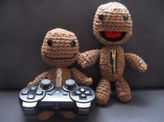 two crocheted toys holding hands with a video game controller in front of them