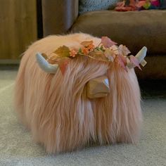 a furry animal with horns and flowers on it's head laying on the floor