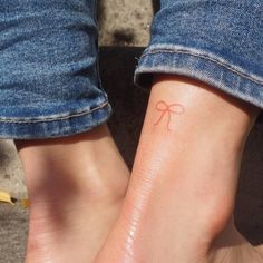 two people's feet with small tattoos on their ankles, both wearing blue jeans