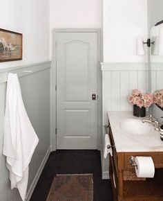 a bathroom with a sink, mirror and towel on the rack next to the door