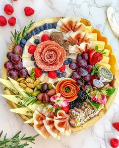 a platter filled with fruit, cheese and crackers on top of a marble counter