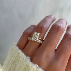 a woman's hand with an engagement ring and diamond band on her left hand