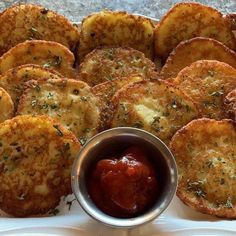 some fried food is on a white plate with a small bowl of ketchup