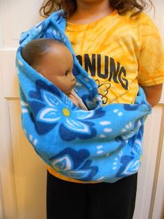 a young child holding a baby doll wrapped in a blue and yellow flowered blanket